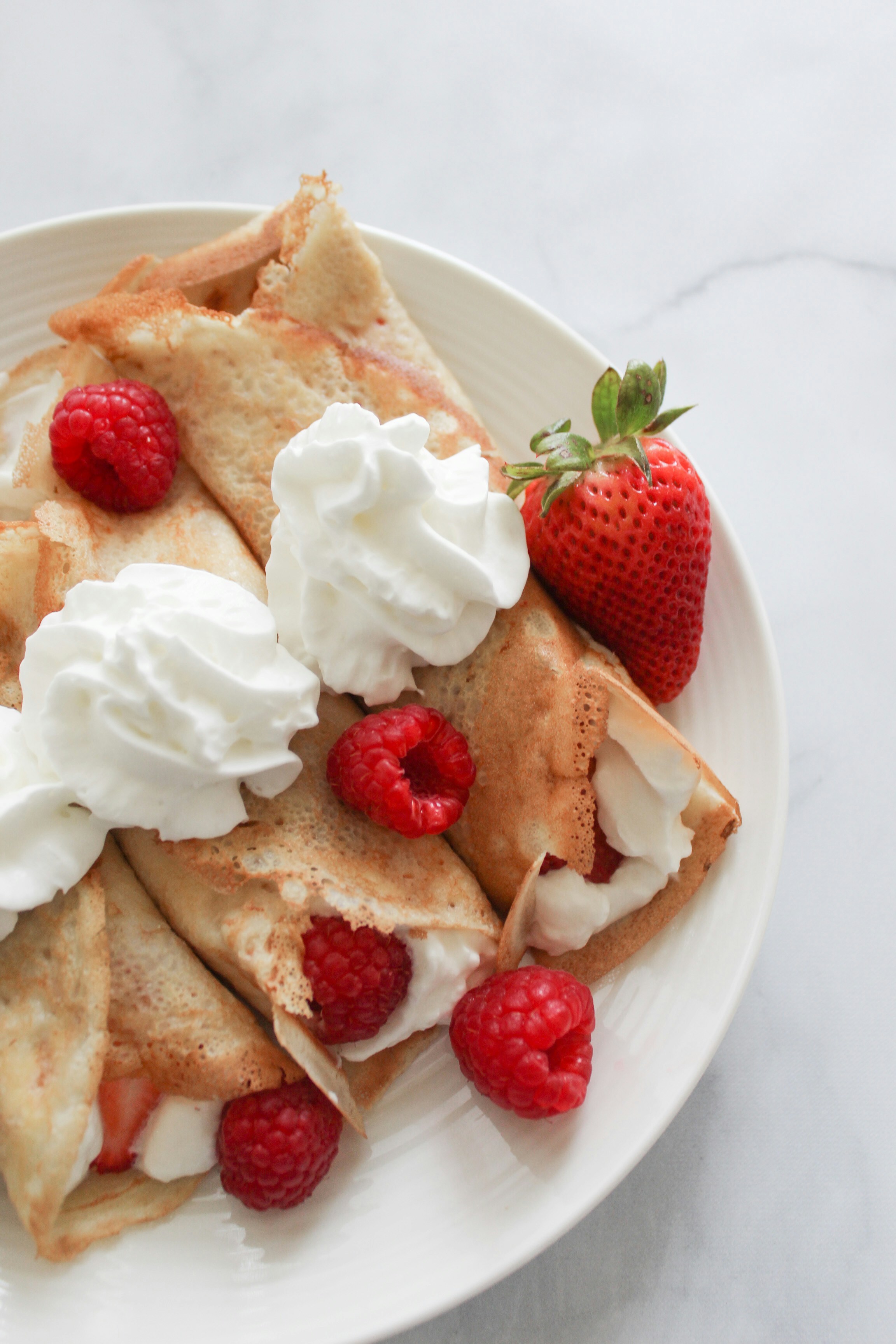 three strawberry crepes on a plate